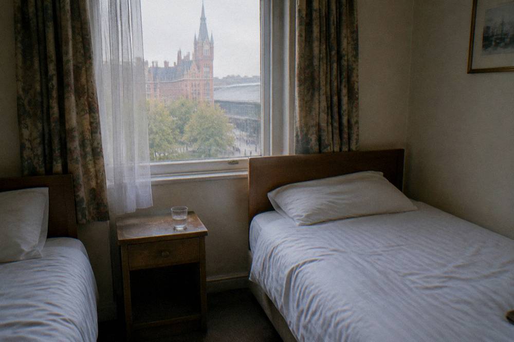 A small budget hotel twin room with two single beds and a bedside table