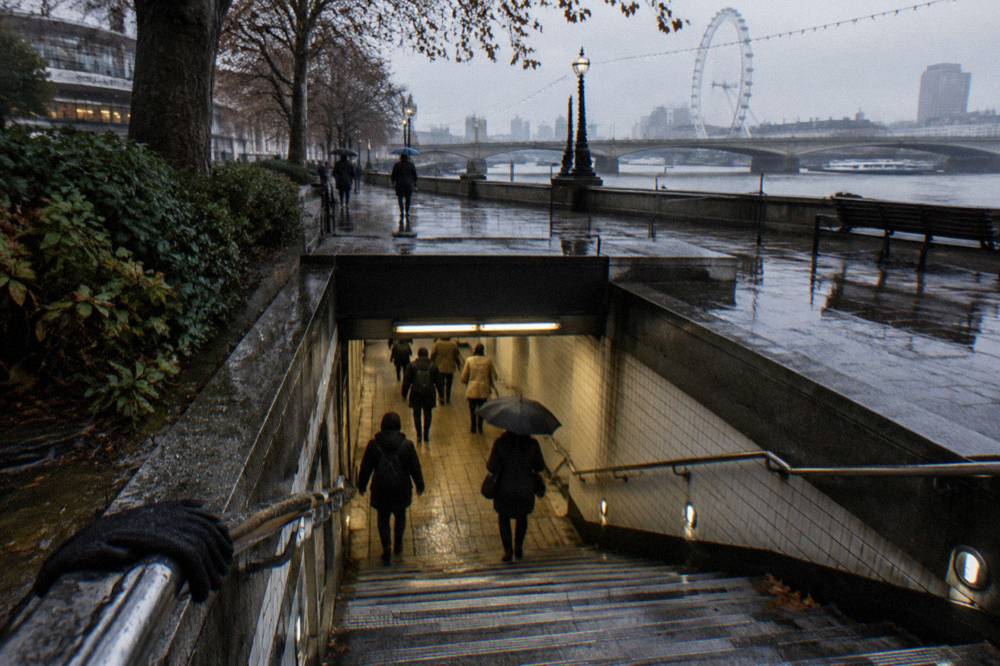 A Tube station entrance with steps descending to a tiled walkway and no readable signage