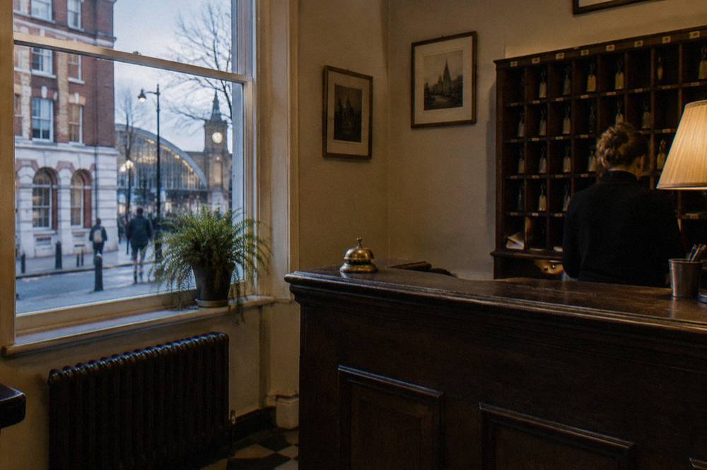 A hotel reception desk with a wooden counter and wall-mounted key racks behind it