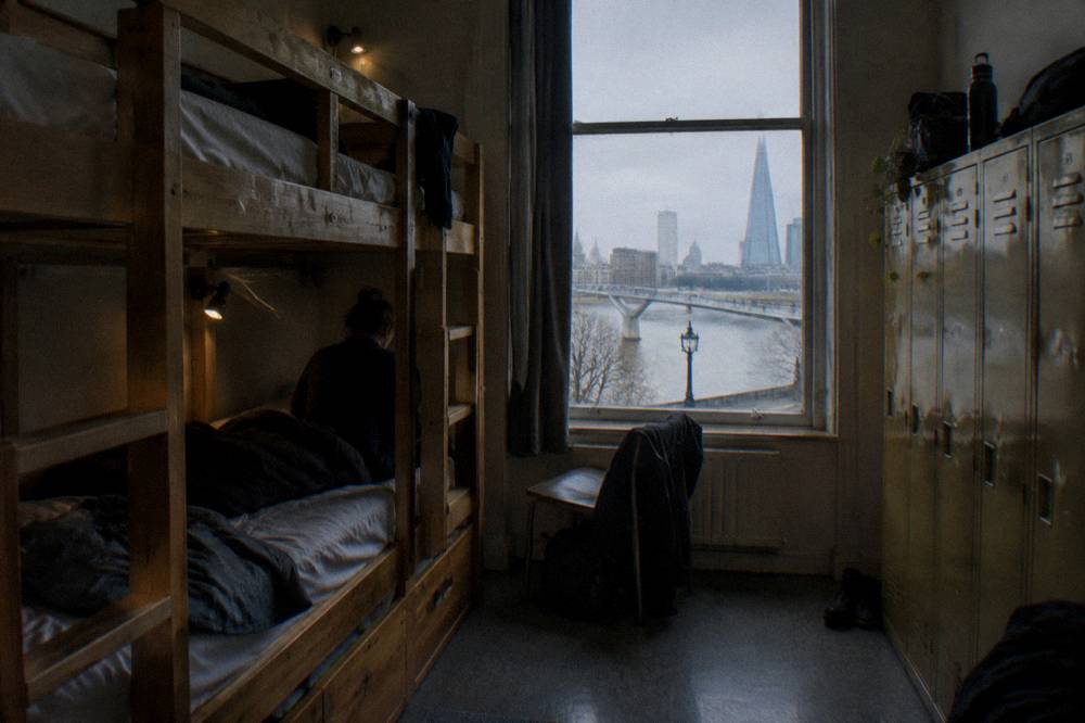 A bunk dorm room with wooden frames, personal reading lights and lockers along one wall