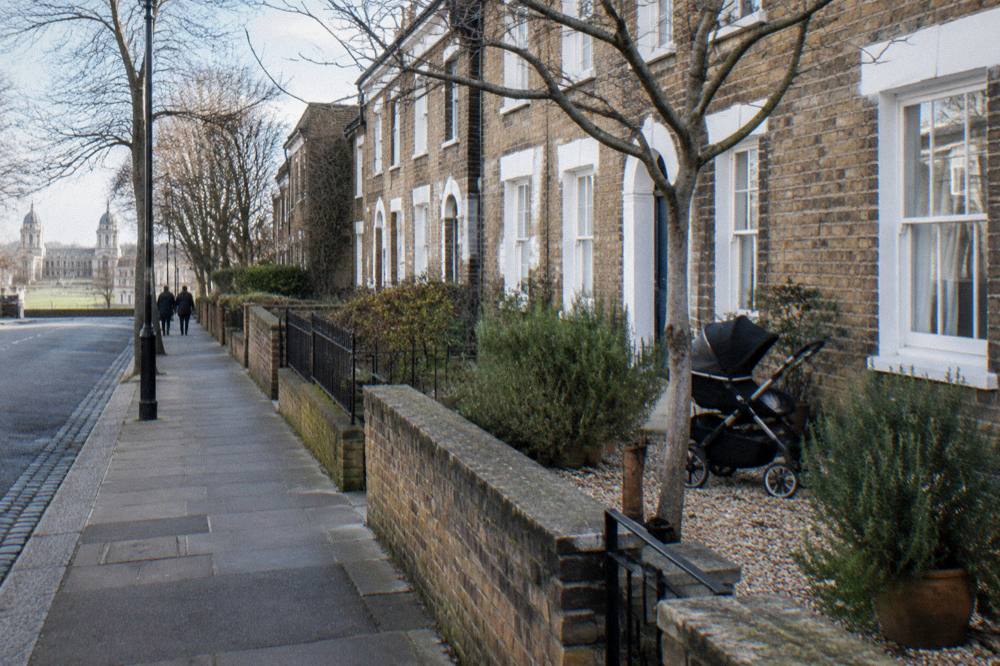 A London terrace of brick townhouses with white sash windows and small front gardens