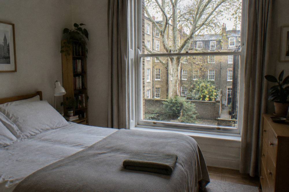 A clean double bedroom in a small flat with a window onto a courtyard
