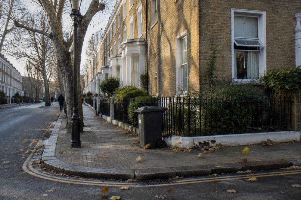 A residential London street of brick terraced houses with plane trees