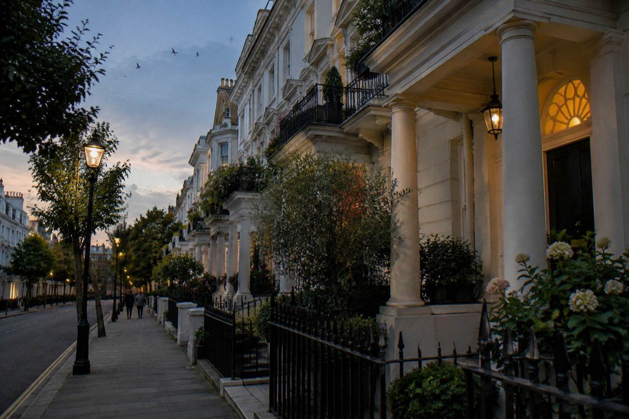 A quiet London terrace street of white stucco townhouses at dusk