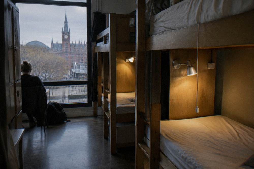 A hostel bunk dorm room with wooden frames and reading lights