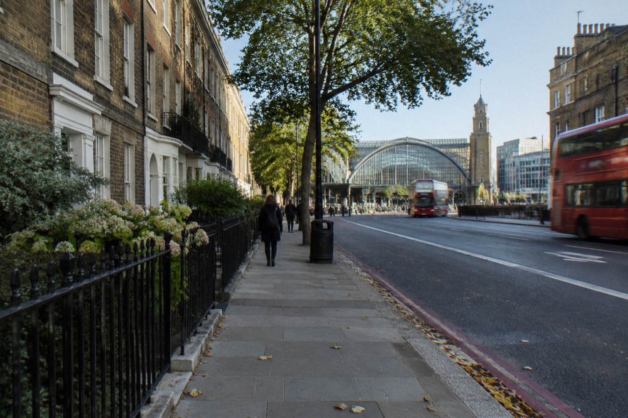 A London street with brick terraces and a station exterior in daylight